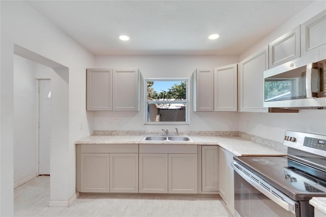 kitchen with light countertops, a sink, appliances with stainless steel finishes, gray cabinetry, and recessed lighting