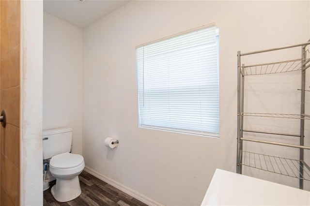 full bathroom featuring baseboards, a tile shower, wood finished floors, and toilet