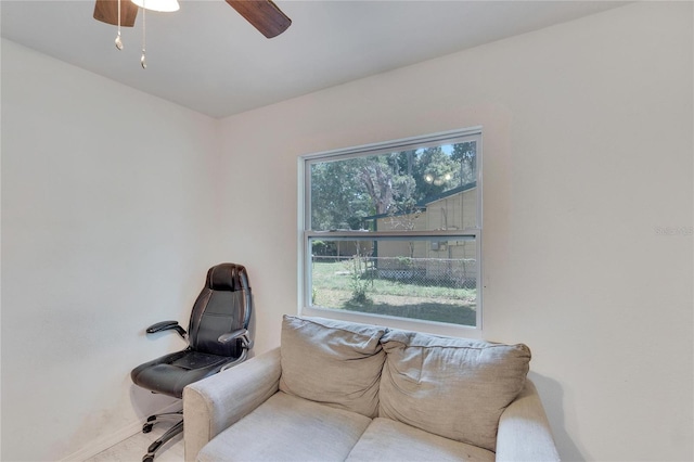 living area featuring baseboards, carpet floors, and a ceiling fan