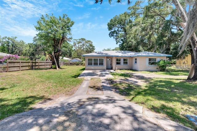 view of front of home featuring stucco siding, fence, a front lawn, and concrete driveway