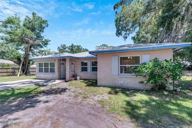 view of front of home featuring fence, a front lawn, and concrete block siding