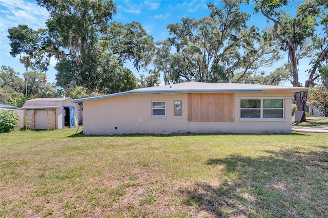 rear view of property featuring a storage unit, concrete block siding, an outdoor structure, and a yard