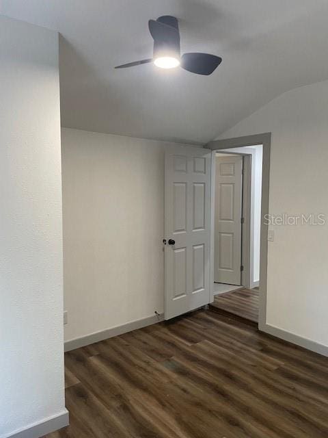 spare room with dark wood-type flooring, vaulted ceiling, and ceiling fan