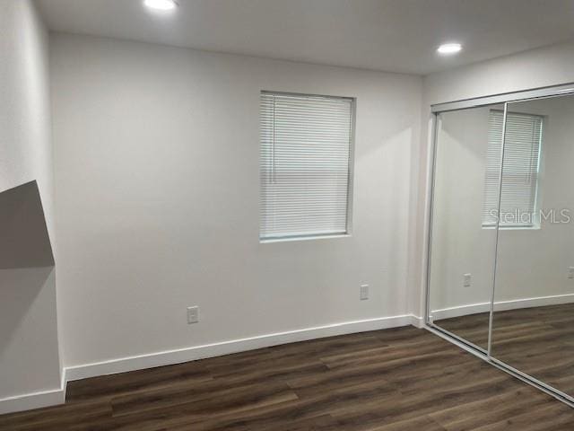 unfurnished bedroom with dark hardwood / wood-style flooring and a closet