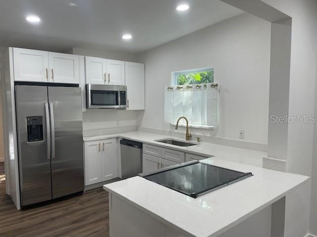 kitchen with white cabinets, kitchen peninsula, stainless steel appliances, and sink