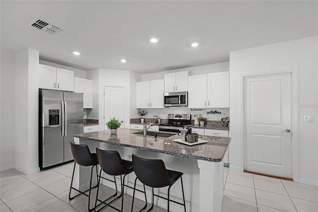 kitchen with an island with sink, sink, stainless steel appliances, and white cabinets