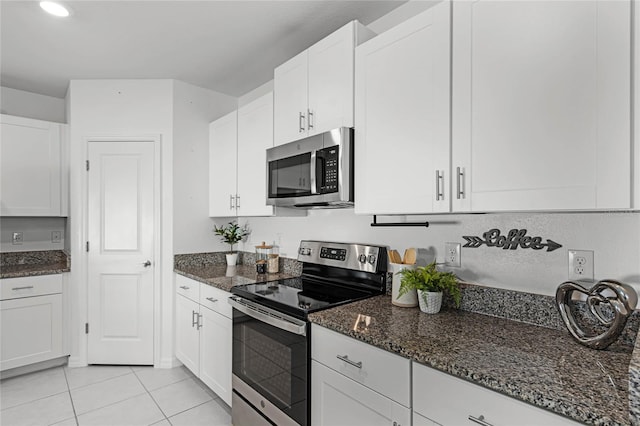 kitchen featuring dark stone countertops, white cabinets, appliances with stainless steel finishes, and light tile patterned floors