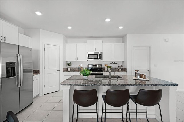 kitchen featuring stainless steel appliances, white cabinetry, a center island with sink, and sink