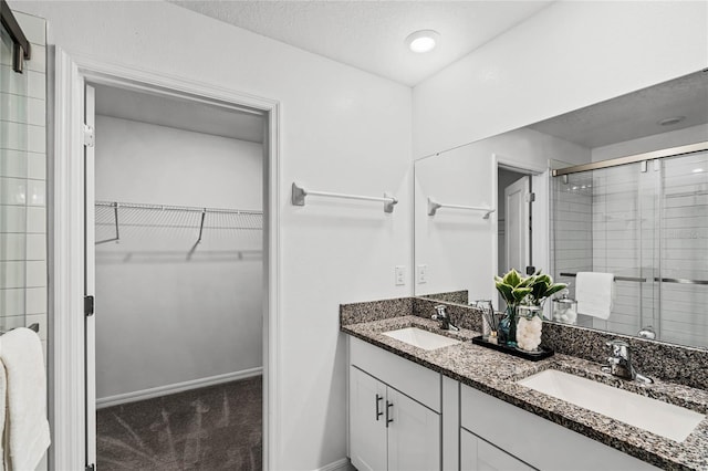 bathroom featuring vanity, a textured ceiling, and a shower with shower door