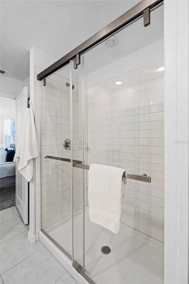 bathroom featuring a textured ceiling, tile patterned flooring, and an enclosed shower