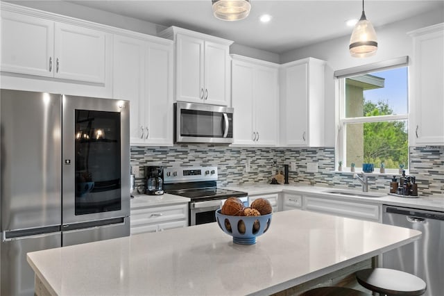 kitchen featuring hanging light fixtures, backsplash, white cabinetry, and stainless steel appliances