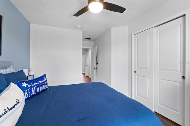 unfurnished bedroom with ceiling fan, a textured ceiling, a closet, and dark hardwood / wood-style flooring