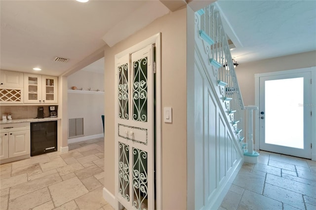 interior space featuring decorative backsplash, wine cooler, and white cabinets