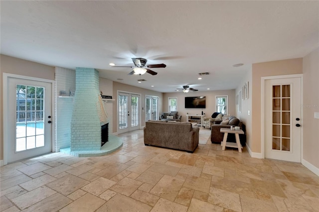 living room featuring ceiling fan, a fireplace, and a healthy amount of sunlight