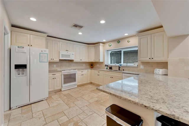 kitchen with decorative backsplash, light stone counters, white appliances, cream cabinets, and sink