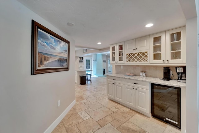 kitchen with white cabinetry, light stone countertops, and wine cooler