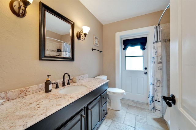 bathroom with curtained shower, vanity, and toilet