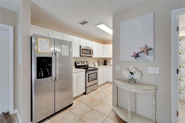 kitchen with white cabinets, appliances with stainless steel finishes, and light tile patterned floors