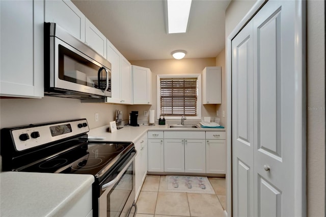 kitchen featuring white cabinetry, sink, light tile patterned floors, and stainless steel appliances