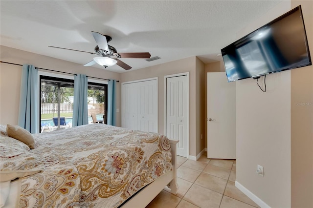 tiled bedroom featuring ceiling fan, multiple closets, a textured ceiling, and access to exterior