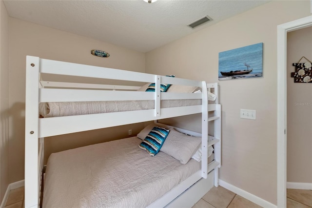 bedroom featuring a textured ceiling and light tile patterned floors