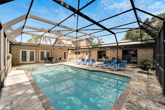 view of pool with french doors, glass enclosure, an in ground hot tub, and a patio area