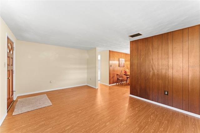 spare room with wooden walls and light wood-type flooring