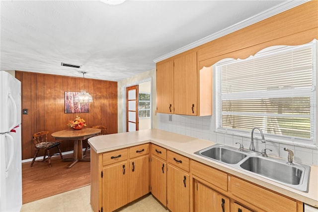 kitchen with white refrigerator, hanging light fixtures, wood walls, and plenty of natural light