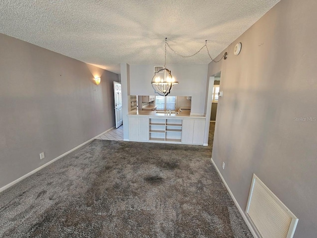 unfurnished dining area with a textured ceiling and light colored carpet