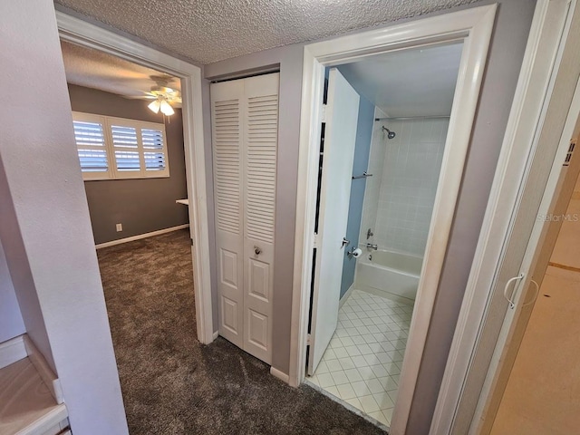 hall with dark carpet and a textured ceiling