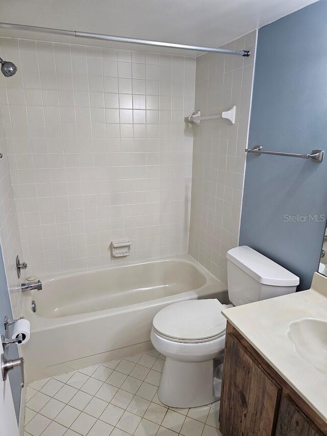 full bathroom with toilet, tiled shower / bath combo, vanity, and tile patterned flooring