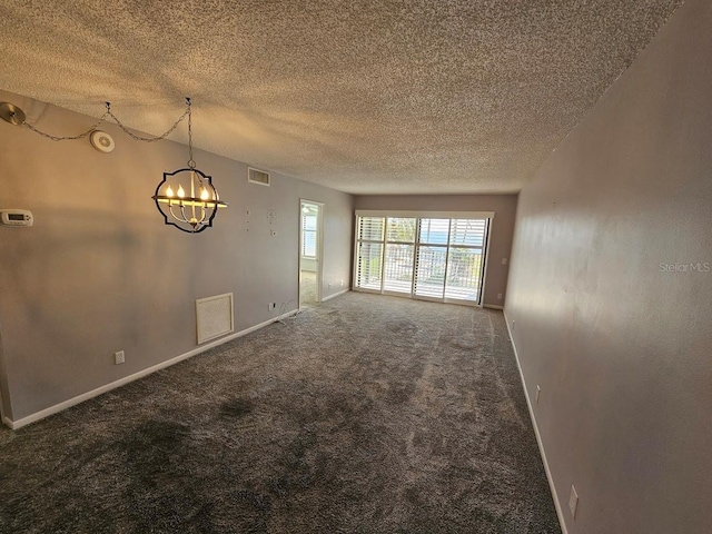 empty room featuring carpet flooring, a textured ceiling, and an inviting chandelier