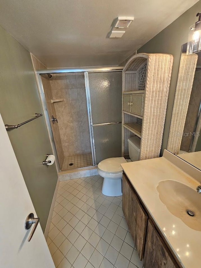 bathroom with toilet, a shower with shower door, vanity, and tile patterned floors