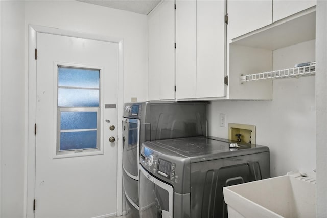 laundry area featuring washing machine and dryer, cabinets, and sink