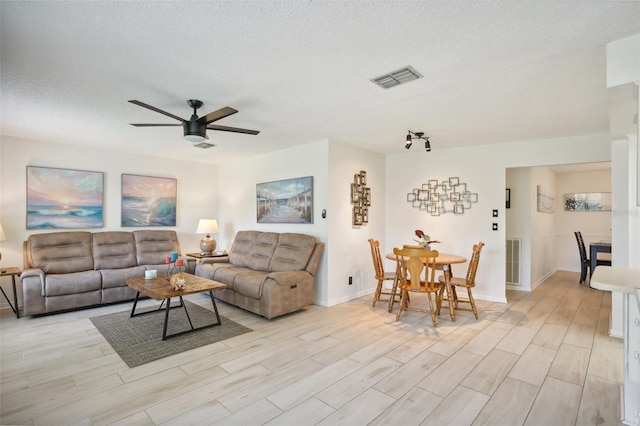 living room featuring a textured ceiling, light hardwood / wood-style floors, and ceiling fan