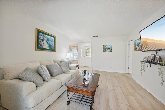 living room with a textured ceiling and light hardwood / wood-style flooring