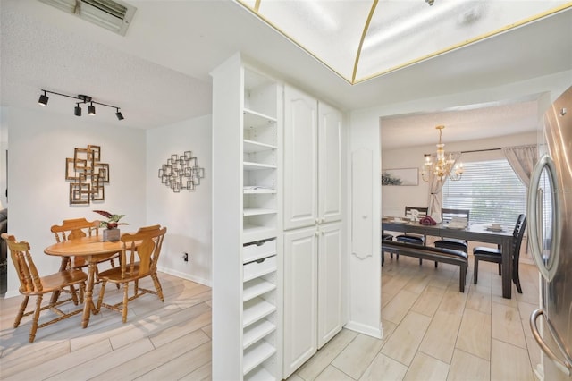 dining space with a textured ceiling, an inviting chandelier, and light hardwood / wood-style flooring