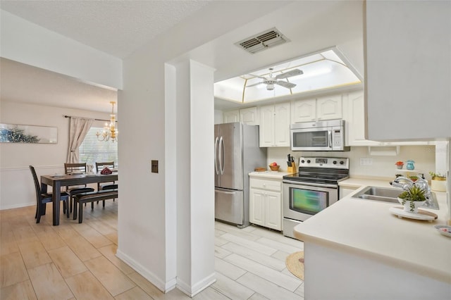 kitchen featuring light hardwood / wood-style floors, white cabinets, a textured ceiling, a raised ceiling, and appliances with stainless steel finishes