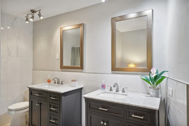 bathroom with tile walls, a shower with curtain, vanity, and toilet