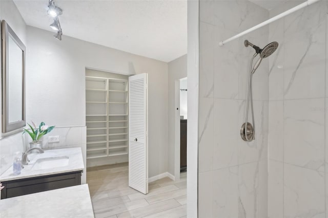 bathroom with vanity, a textured ceiling, and a tile shower