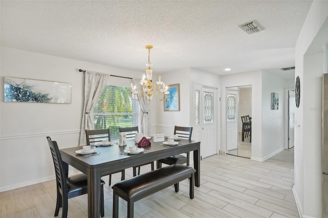 dining room with light hardwood / wood-style flooring, a notable chandelier, and a textured ceiling