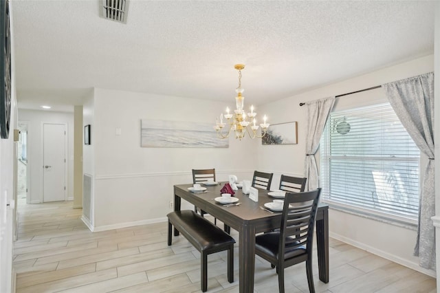 dining room with an inviting chandelier, light hardwood / wood-style floors, and a textured ceiling