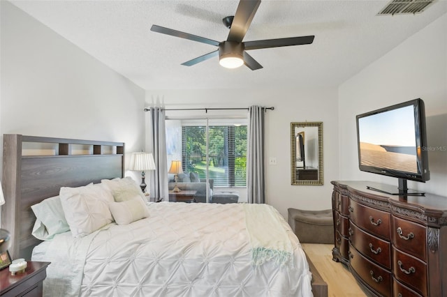 bedroom with ceiling fan, a textured ceiling, and light wood-type flooring