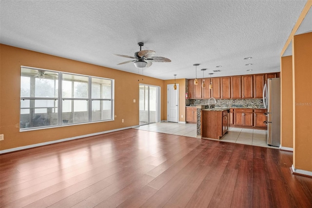 kitchen with ceiling fan, pendant lighting, light hardwood / wood-style flooring, stainless steel refrigerator, and a center island