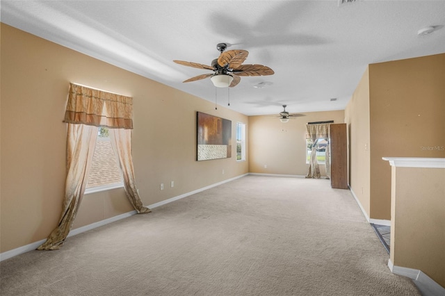 carpeted spare room with ceiling fan and plenty of natural light