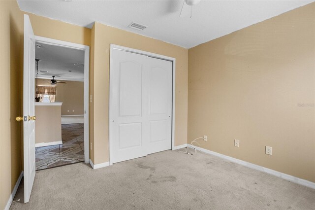 unfurnished bedroom with light carpet and a closet