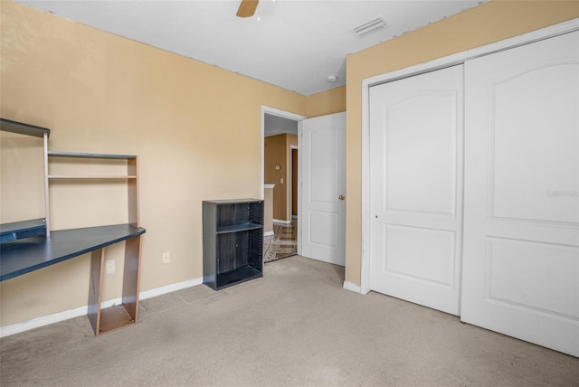 unfurnished bedroom featuring ceiling fan, light colored carpet, and a closet