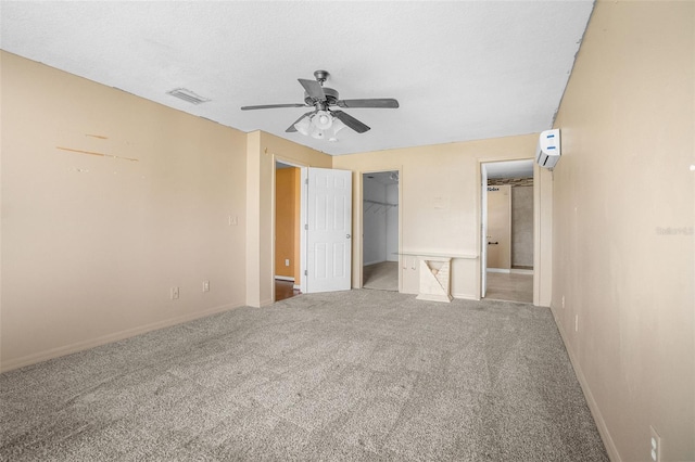 unfurnished bedroom with a closet, a textured ceiling, carpet, a walk in closet, and ceiling fan