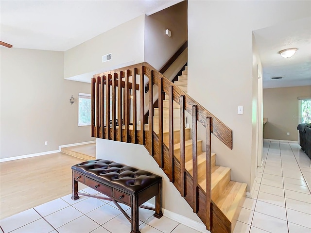 stairway featuring tile patterned flooring, vaulted ceiling, and plenty of natural light