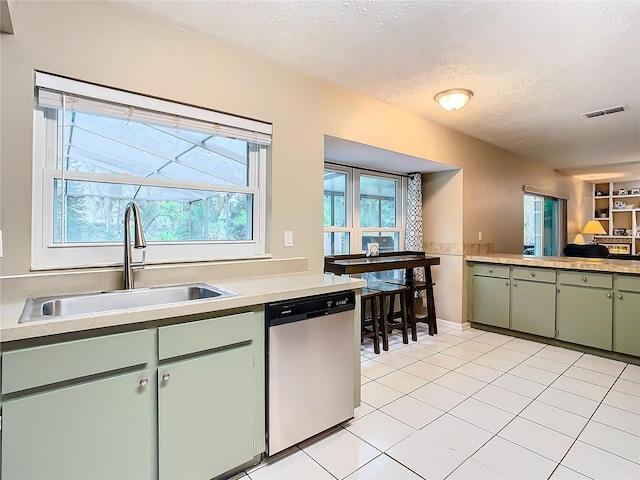 kitchen with dishwasher, light tile patterned floors, a textured ceiling, sink, and green cabinets